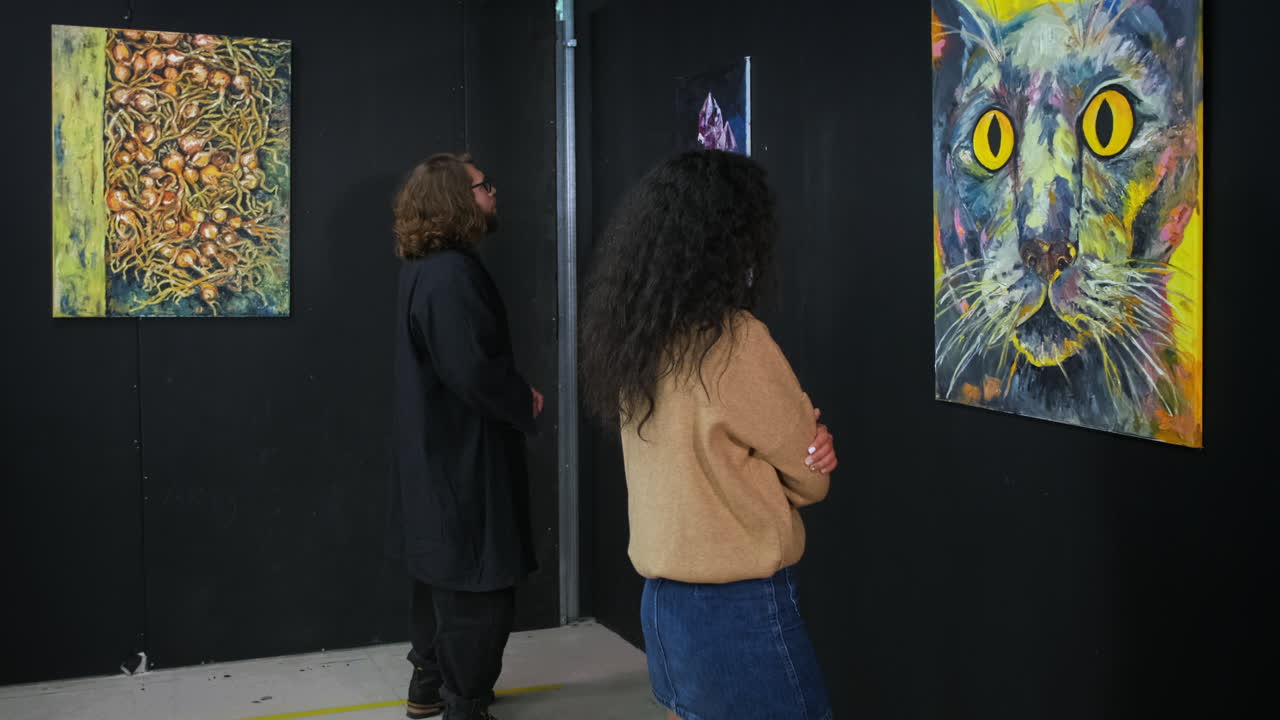 예술 갤러리에서 추상적이고 비유적인 그림을 보는 사람들