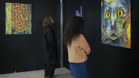 personas que ven pinturas abstractas y figurativas en una galería de arte