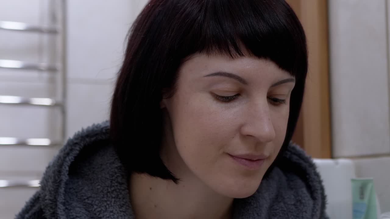 mujer hidrata la piel seca alrededor de los ojos, usando parches coreanos frente al espejo