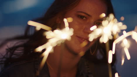 close-up-sparklers-portrait-of-beautiful-caucasian-woman-celebrating-new-years-eve-enjoying-independence-day-celebration-on-beach-at-sunset