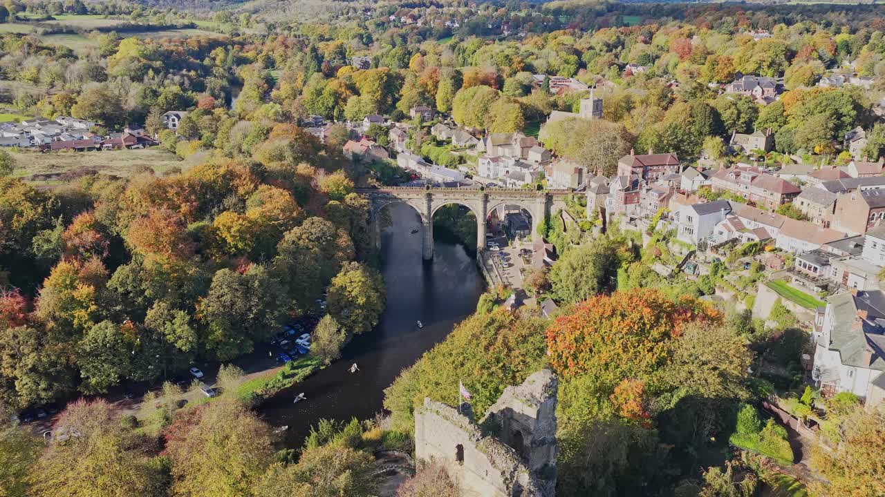 Vista aerea del viadotto vittoriano di Knaresborough in pietra a più arcate, che trasporta la ferrovia di Harrogate sul fiume Nidd, con le rovine del castello e il bosco su una sponda e la città sull'altra