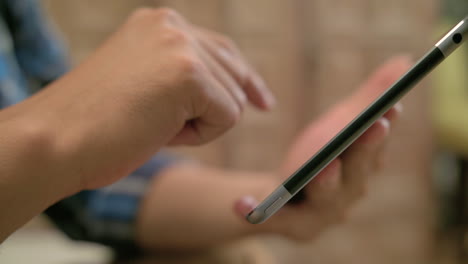 slow-mo, close up of a man's hand using tablet and zooming it in