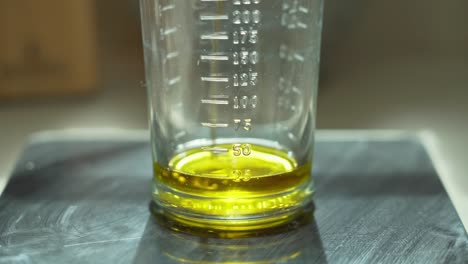 close up pouring sun flower oil in a measuring cup, shallow focus