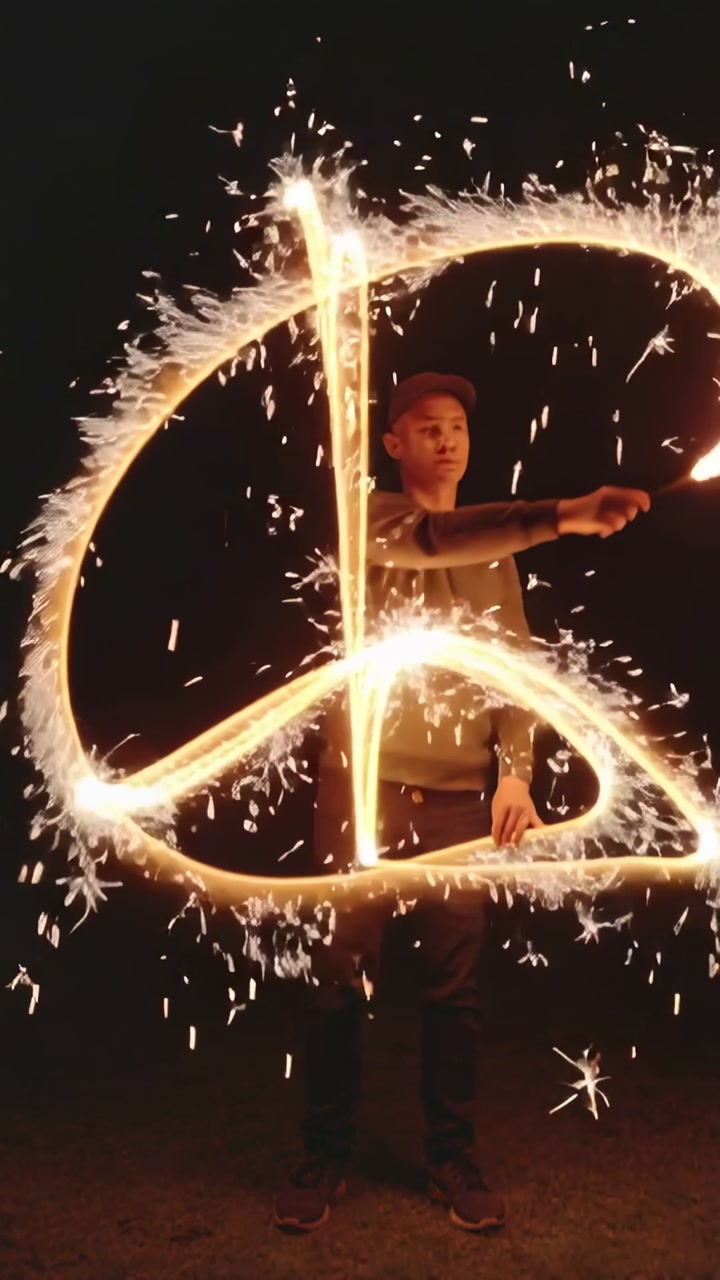 Man Light Painting a Peace Sign with Sparklers in the Dark