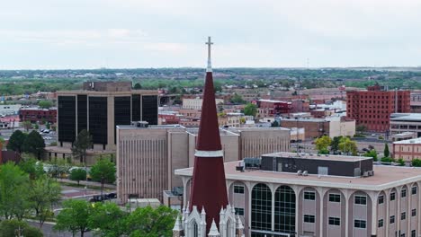 drones orbitan por encima de la cruz con el fondo de la ciudad urbana en pueblo colorado