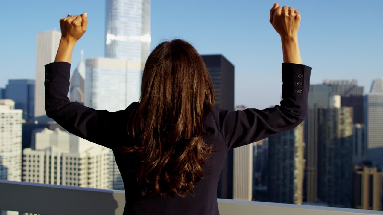 una mujer de negocios hispana celebrando el éxito en el techo con vistas a chicago.