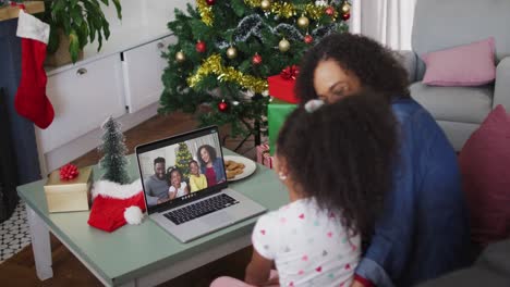 Happy-african-american-mother-and-daughter-on-video-call-with-family-at-christmas-time