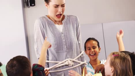 Playful-schoolchildren-tied-up-female-teacher-with-rope