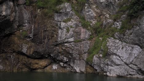 woman throwing stone into the crystal clear water of lake ledro in italy