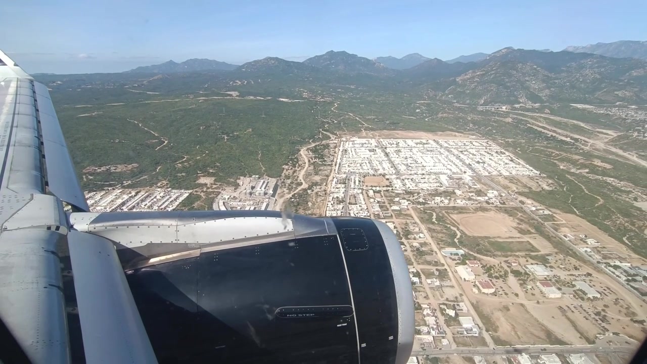 Ripresa POV che guarda fuori dal finestrino di un aereo sull'ala e sul motore con la terra sottostante
