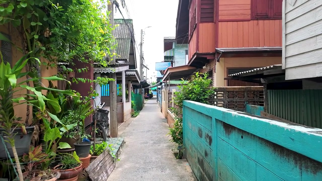 A slow forward tracking shot through a narrow residential alleyway with traditional wooden architecture.