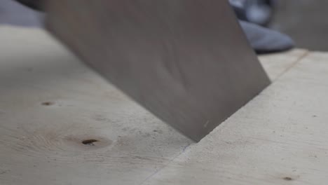 un trabajador con guantes cortando la madera con una línea marcada - primer plano