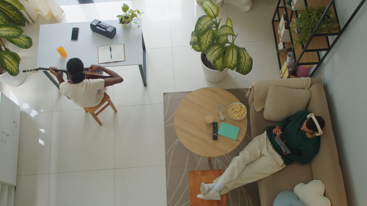 Female Songwriter Practicing Guitar Chords, Male Graphic Designer Using Tablet