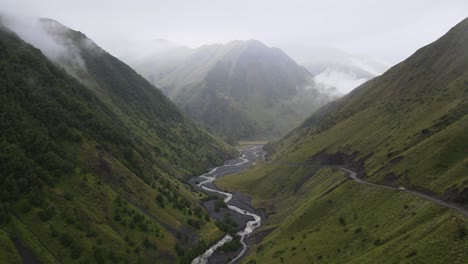 A-breathtaking-view-of-caucasian-mountains-range,-with-a-winding-river-cutting-through-the-lush-green-valleys