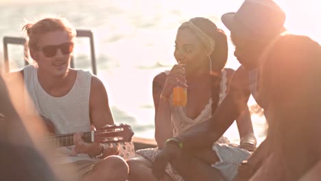 multi-ethnic hipster friends having fun playing the guitar on jetty