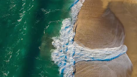 Cenital-view-of-the-sea-and-the-waves-on-a-spring-day,-blue,-green-and-orange-combinatios