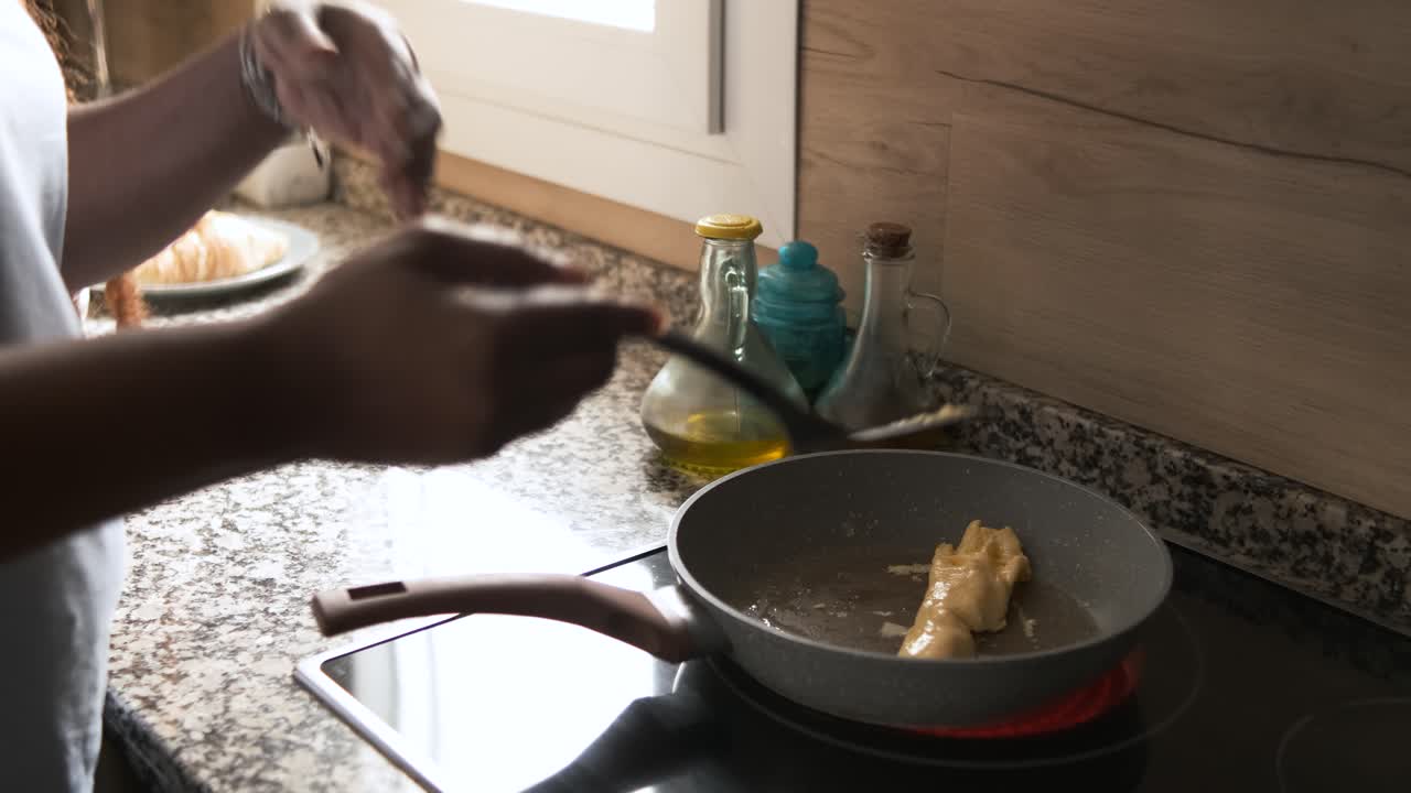 Person cooking eggs in a frying pan in a kitchen