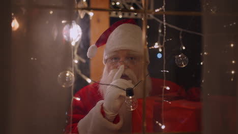 portrait of santa claus looking out the window and putting his finger to his face and saying shh