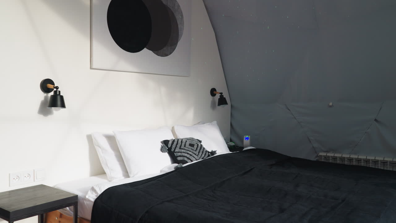 Bedroom for tourists in glamping tent. Double bed with linen blanket in tone with lamps on wall. Space for tourists looking for comfortable retreat