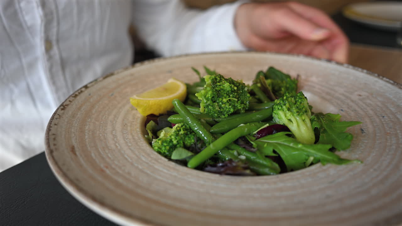 Healthy vegetable salad with broccoli, green beans, and lemon wedge served on plate