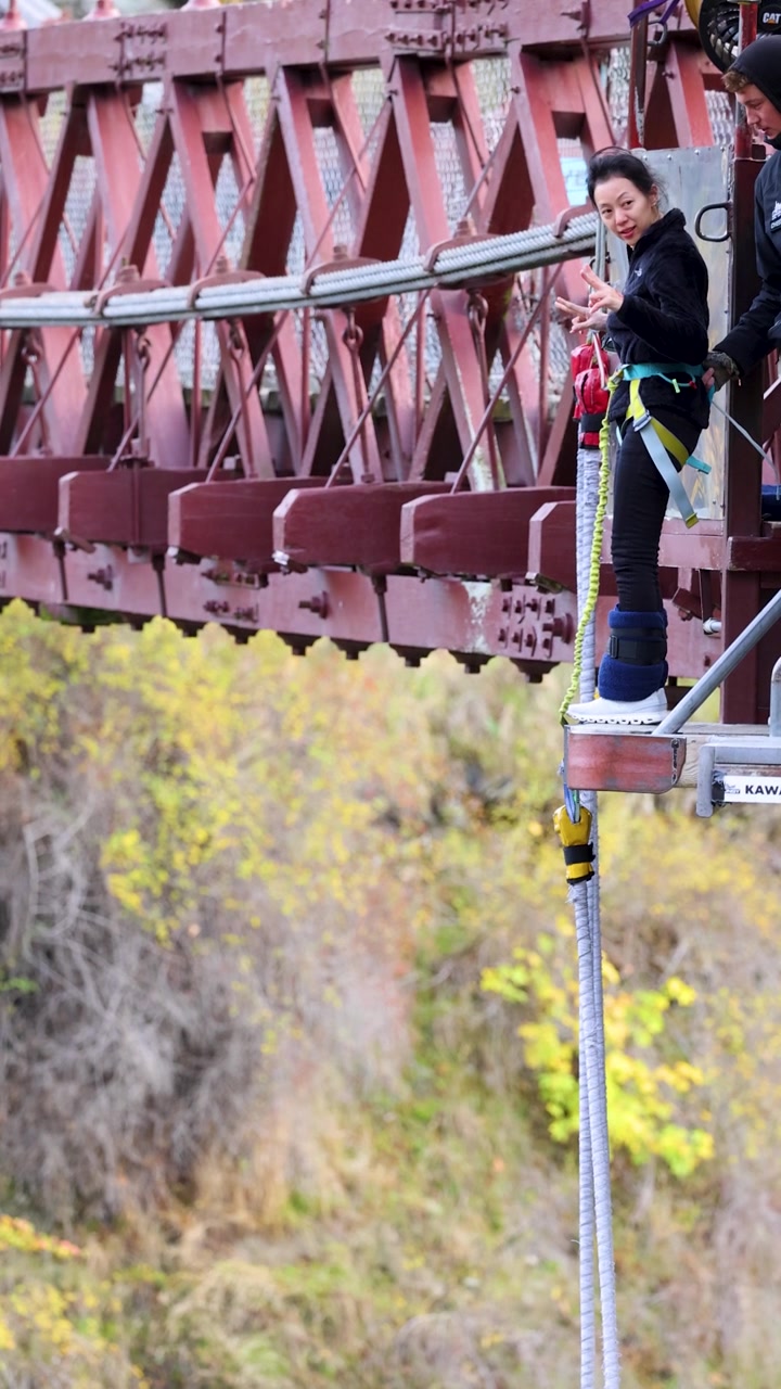 Una persona si prepara per un bungee jumping da un ponte a Queenstown, Nuova Zelanda, mostrando attesa ed eccitazione.