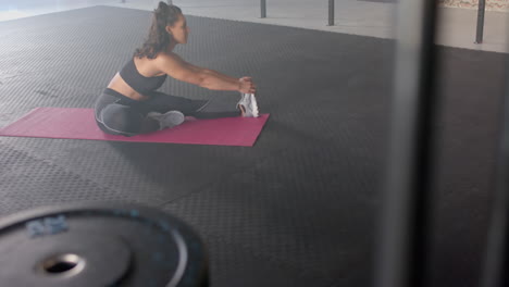 stretching on yoga mat, strong fit woman in gym wearing sportswear, focusing on flexibility, copy sp