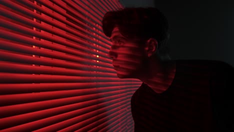 young person looking out a window at night