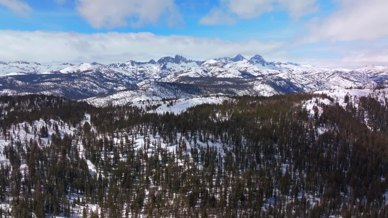 Minarets jagged towering peaks vista point panoramic landscape Mammoth Mountain ski resort aerial drone California winter spring sunny blue sky morning clouds Hemlocks Inyo National Forest forward