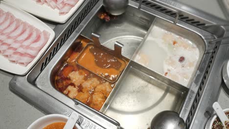 panning-view-of-szechuan-hotpot-style-with-boiling-soup-and-pork-sliced-on-table