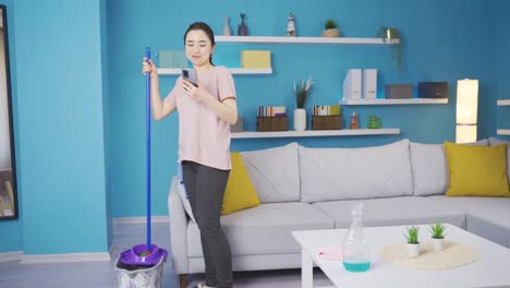 Mujer-Joven-Asiática-Limpiando-Mientras-Habla-Cara-A-Cara-Por-Teléfono.