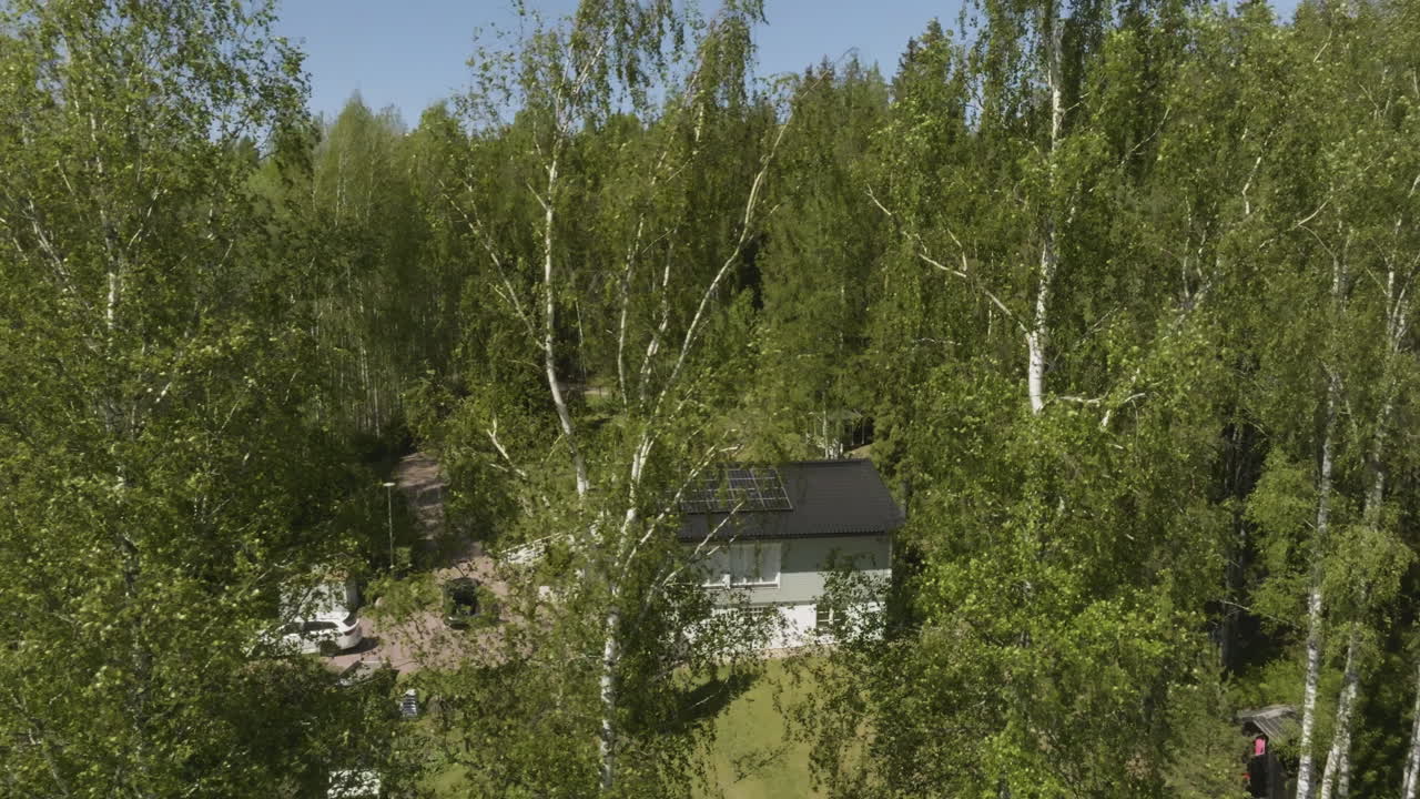 Drone circling a spring colored tree, revealing a solar home and EV cars on yard