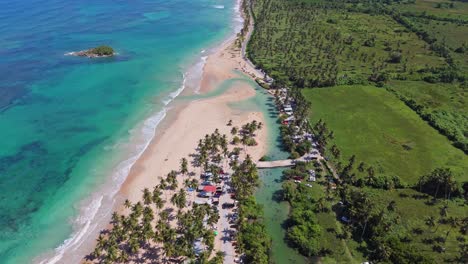 aerial view of turquoise playa la estrada with palm tress at sunny day. tourist and people swimming in clear rivers, flowing into carribean sea. cabrera, maria trinidad sanchez.