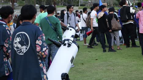 people observing through telescopes in a park