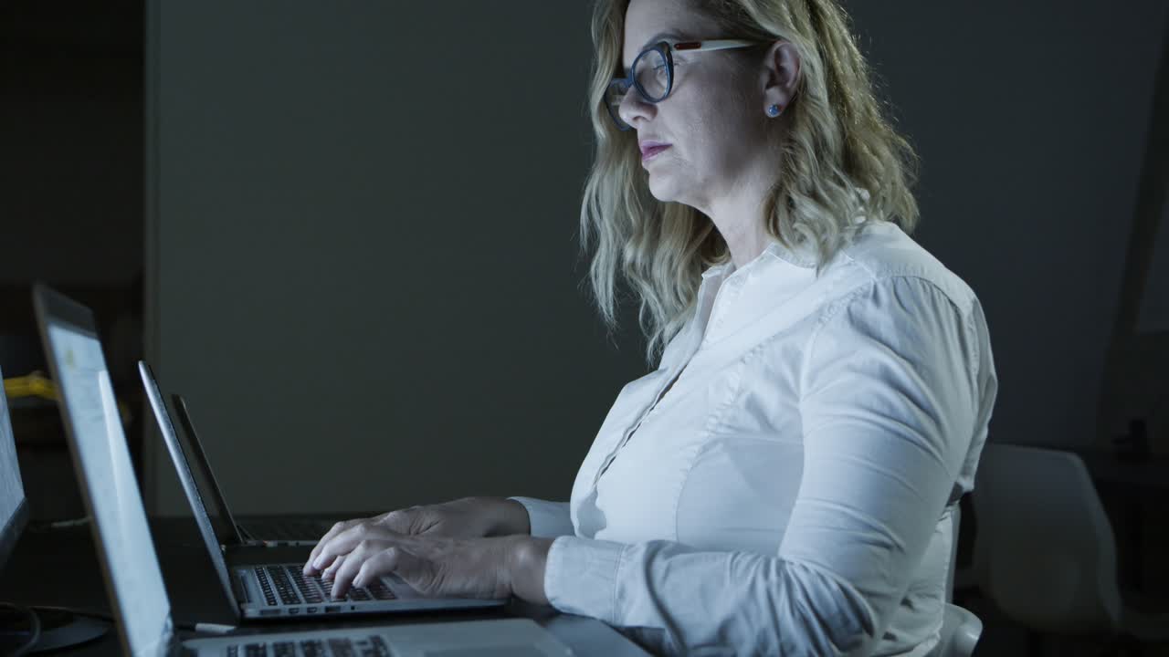 Focused businesswoman in eyeglasses using laptop