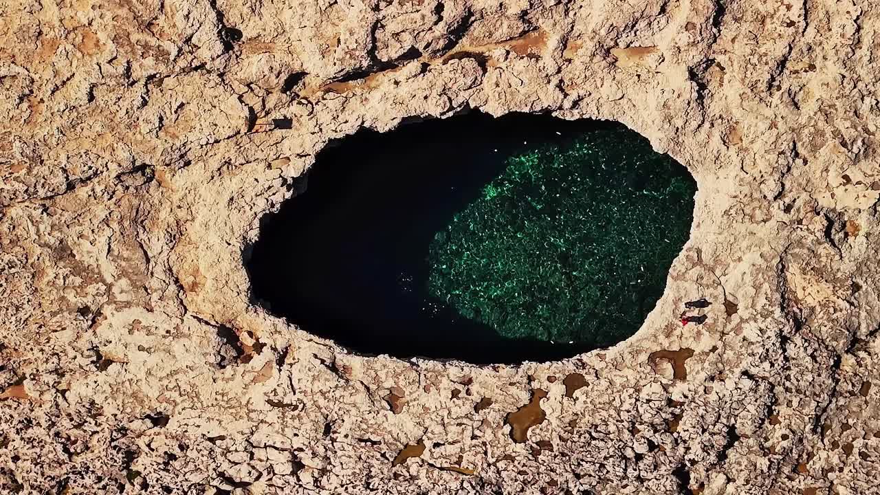 日中のマルタにある自然の岩のプールにある濃い青色の水