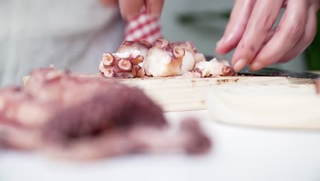 persona caucásica con manos viejas poniendo trozos de pulpo en un plato para cocinar