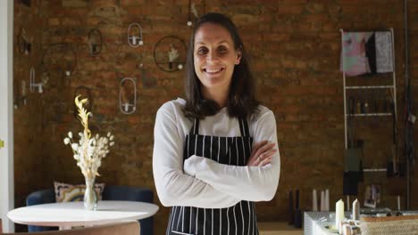 Smiling-caucasian-female-business-owner-with-crossed-hands,-wearing-striped-apron-looking-at-camera