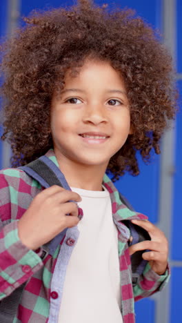 vertical video: in school, young biracial male student with curly brown hair is smiling