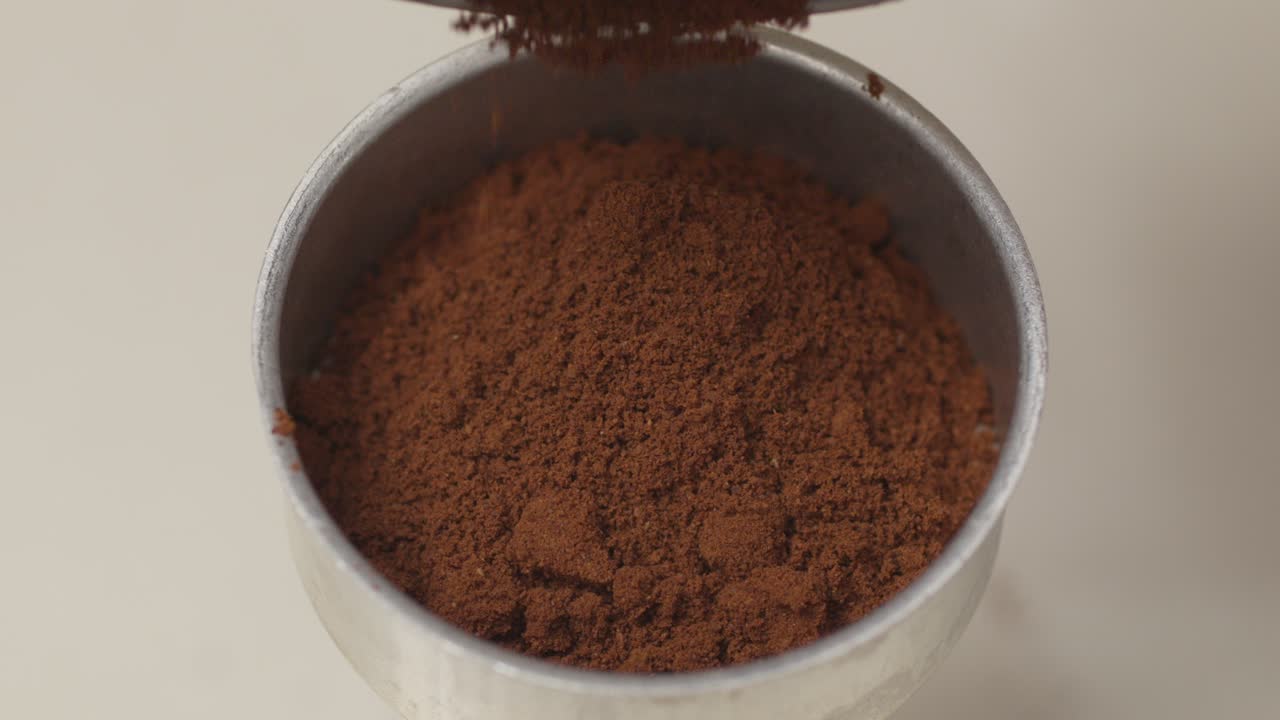 Freshly ground coffee spilling onto a surface, close-up shot of coffee grounds