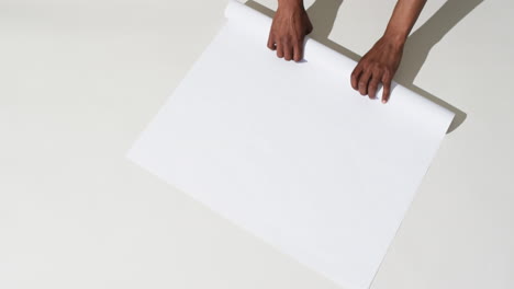 Video-of-hands-of-african-american-man-with-rolling-up-white-paper-on-white-background