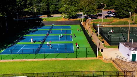 aerial drone shot slowly rotating above athletes on a tennis court playing a pickle ball tournament in atlanta, georgia