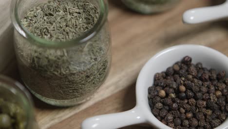 Close-up-panning-shot-of-thyme-and-black-pepper-sitting-in-small-jars