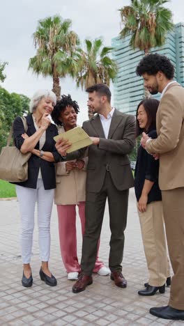 a group of business people looking at a tablet outdoors