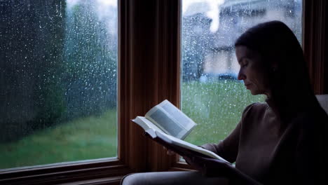 woman reading by the window on a rainy day