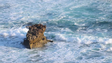 waves crashing against a solitary rock formation