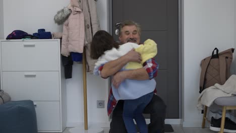 hombre maduro feliz abrazando a su nieta llegando a casa