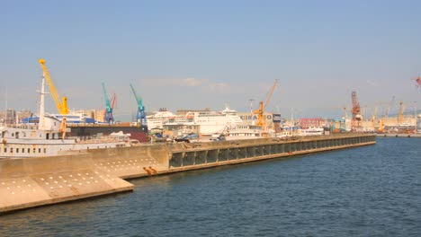 Pan-shot-of-ships-arriving-at-Naples-port-in-Naples,-Italy-with-mountains-in-the-background-on-a-sunny-day