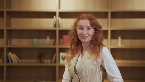 an attractive red-haired woman looks smiling into the camera