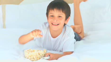 a little boy eating popcorn in front of the tv