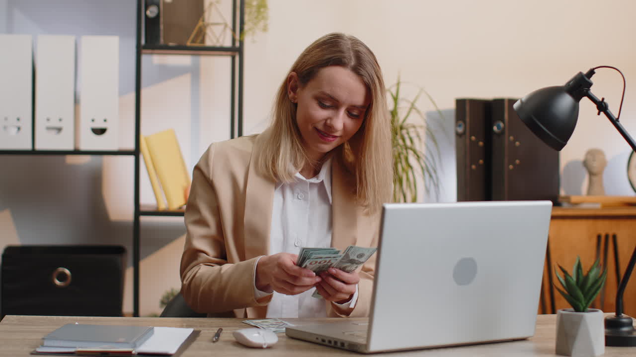 Rich businesswoman in suit working on laptop pc counting money cash calculate earnings income profit